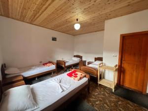 una camera con tre letti e un soffitto in legno di Guest House Gjelaj a Theth Altre 34 foto