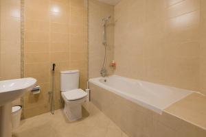 a bathroom with a tub and a toilet and a sink at GREAT 3 Bedroom Apartment Beach Front (Side View) in Abu Dhabi