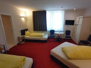 um quarto de hotel com duas camas e uma mesa e cadeiras em Hotel im Klosterring em Villingen-Schwenningen