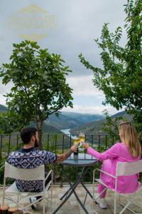 a man and woman sitting at a table with wine glasses at Refúgio da Suite 4 in Pinhão