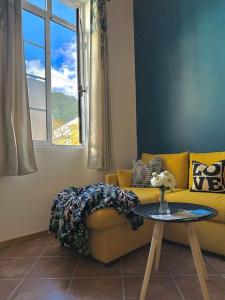 a living room with a yellow couch and a table at Apartamento das Fontes in Furnas