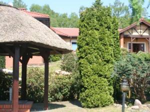 a large tree next to a house with a thatch roof at Apartament II Marysieńka in Kąty Rybackie