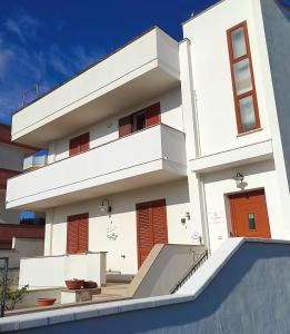 - un bâtiment blanc avec des portes et des escaliers orange dans l'établissement B&B La Mimosa, à Castro di Lecce