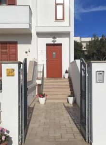 une maison blanche avec une porte rouge et des escaliers dans l'établissement B&B La Mimosa, à Castro di Lecce