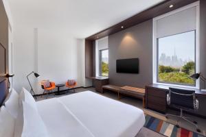 a hotel room with a bed and a tv at Aloft Al Mina, Dubai Jumeirah in Dubai