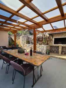 a wooden table and chairs on a patio with a stone wall at Apartman Roza in Ploče