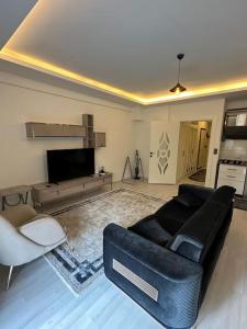 a living room with a black couch and a tv at Close to the beach (150 m.) and central locations in Antalya