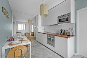 a kitchen with white cabinets and a table with chairs at Le Jolimont T4 et vues spectaculaires sur la ville in Toulouse