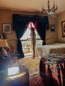 a woman standing in a bedroom looking out the window at chaisheeka in Mellieħa