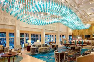 a lobby with a large chandelier and tables and chairs at Sheraton Bandung Hotel & Towers in Bandung