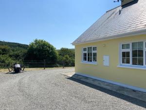 a house with a gravel driveway next to a building at Tilly's Cottage in Durrus