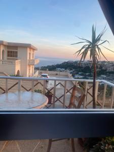 a balcony with a table and a palm tree at sunrise flats in Mellieħa