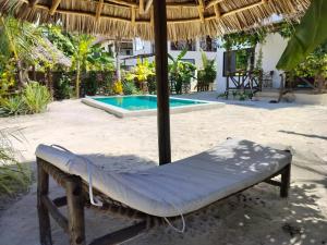 a bed under a straw umbrella next to a swimming pool at Sand Beach Boutique Villas in Bwejuu