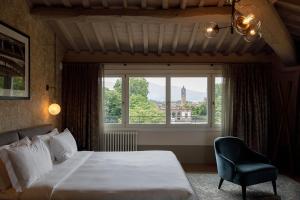 ein Schlafzimmer mit einem Bett, einem Stuhl und einem Fenster in der Unterkunft Grand Universe La Residenza in Lucca