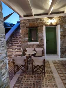 un patio con una puerta verde y sillas en una pared de piedra en ΤΟ ΚΑΜΙΝΙ ΤΟΥ ΜΗΛΑ en Kíthnos