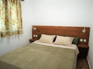 a bedroom with a bed with a wooden headboard and curtains at ΤΟ ΚΑΜΙΝΙ ΤΟΥ ΜΗΛΑ in Kithnos