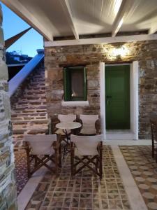 a patio with a green door and chairs at ΤΟ ΚΑΜΙΝΙ ΤΟΥ ΜΗΛΑ in Kithnos