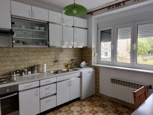 eine Küche mit weißen Schränken und einem Waschbecken in der Unterkunft Apartment Central in Knin