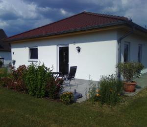 una casa blanca con una silla delante en FeWoMeißner en Wittingen