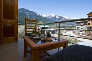 a balcony with a table and a view of a mountain at Hotel Neha Regency in Manāli