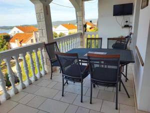 balkon ze stołem, krzesłami i telewizorem w obiekcie Apartments Dodik w Orebiciu