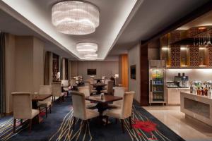 a restaurant with tables and chairs and a bar at Sheraton Zhenjiang Hotel in Zhenjiang