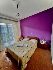 een slaapkamer met een groot bed met een paarse muur bij Kolovos House in Karyes