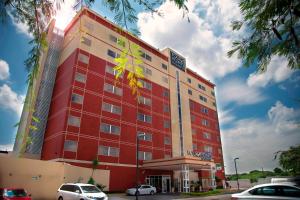 een rood gebouw met auto's ervoor geparkeerd bij Four Points by Sheraton Queretaro Norte in Querétaro