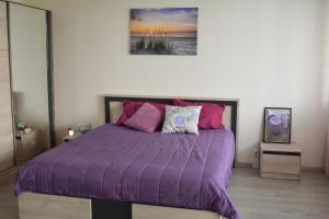 a bed with a purple comforter in a bedroom at City Center Apartment with a Backyard in Burgas City