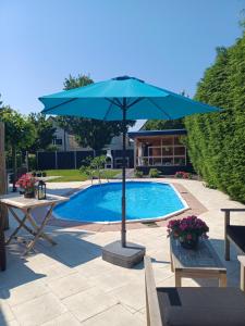 una sombrilla azul junto a una piscina en East Meets West Bed and Breakfast en Veenendaal