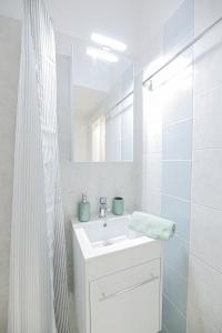 Baño blanco con lavabo y espejo en Uranus Apartment, en Tesalónica