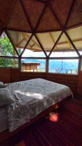 Cama grande en habitación con ventana grande en Domo Geodésico frente al Cañón del Chicamocha, en Los Santos