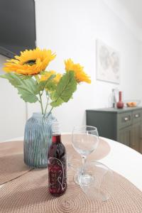 una botella de vino junto a una copa y un jarrón con flores en Uranus Apartment, en Tesalónica