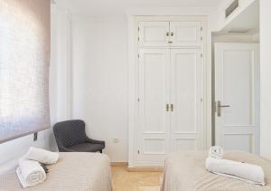 Un dormitorio blanco con 2 camas y una silla en Marina XI Lovely apartment inside Wyndham Resort en Mijas Costa
