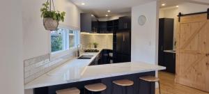 a kitchen with a large white counter and stools at Live - Play - Stay - East Geelong in Geelong