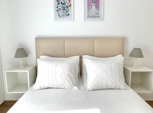 a bed with white pillows and two night stands at Bedrooms AP Garden in Lagos