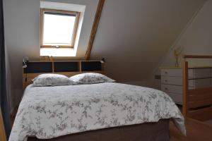 a bedroom with a bed with a floral bedspread and a window at Gîte An Daou Tok in Mellionnec