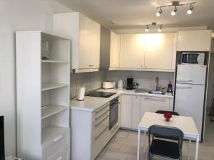 uma cozinha com armários brancos, uma mesa e um frigorífico em ALOE Suite Laurent-Gael em Playa del Inglés