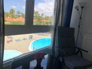 een kamer met een raam met uitzicht op een zwembad bij ALOE Suite Laurent-Gael in Playa del Inglés