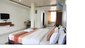 a bedroom with a large bed with white sheets and pillows at SAN NAEL LA RESORT in Cherrapunji