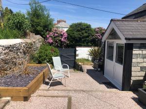 a garden with two chairs and a small shed at Bracken's Retreat in Lostwithiel