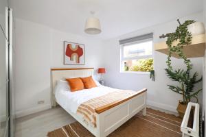 a bedroom with a bed with orange pillows and a window at W London apt for 4. Open plan kitchen/living room in London