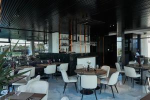 a restaurant with tables and white chairs and windows at WHITE HILLS HOTEL spa&sport in Uzhhorod