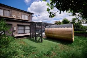 ein großes Holzfass neben einem Haus in der Unterkunft tocoro. Mt.Fuji Uzuki in Fujikawaguchiko