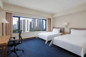 a hotel room with two beds and a desk and a window at Le Meridien Jakarta in Jakarta