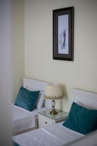 um quarto com duas camas com almofadas azuis e um candeeiro em Crown Hotel em Kutaisi