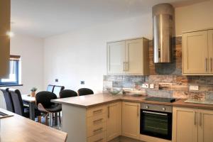 a kitchen with white cabinets and a table and chairs at Queensgate Holiday Cottage Beverley with Parking in Beverley