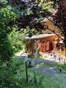 une maison avec une terrasse couverte et une cour arborée dans l'établissement Kutscherhaus am Weiher, à Hundsdorf