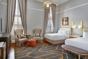 una camera d'albergo con due letti, sedie e TV di The Tremont House, Galveston, a Tribute Portfolio Hotel a Galveston
