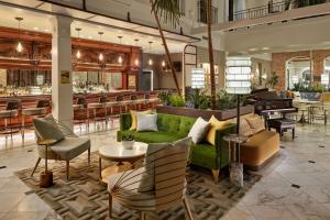 um átrio com um sofá verde e cadeiras e um bar em The Tremont House, Galveston, a Tribute Portfolio Hotel em Galveston